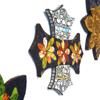 Three colorful mosaic wall art pieces shaped like a cross and flowers are displayed against a white background.