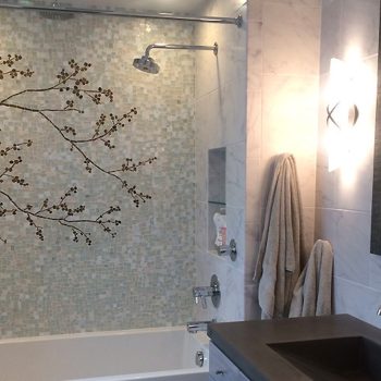 SOLD Bathroom with a bathtub, mosaic tile wall featuring a tree branch design, towels hanging, and a modern vanity.