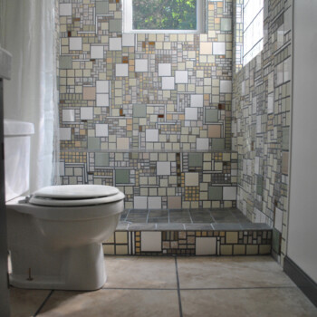 SOLD Bathroom with a toilet and a shower area featuring a geometric mosaic tile wall and natural light from a small window.