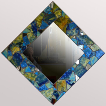 Square mirror with a blue and green mosaic frame, reflecting a window, a person, and a cat in the background.