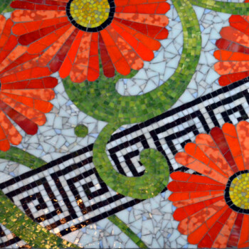 Mosaic featuring large red-orange flowers, green vines, and a black-and-white geometric border pattern.