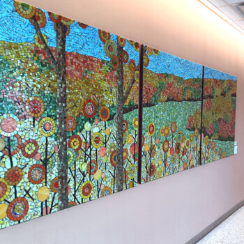 SOLD A colorful mosaic mural depicting a landscape with trees, flowers, and a blue sky hangs on a hallway wall.
