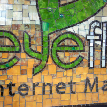 Mosaic sign with the text “eyeflo Internet Marke…” in green and yellow tiles, partially obscured.