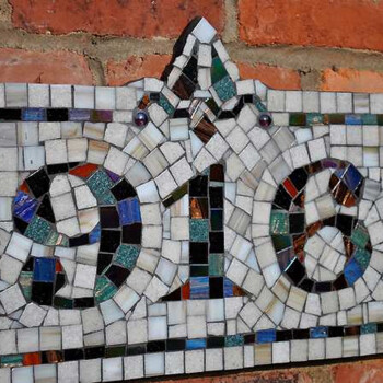 Mosaic house number plaque reading "916" mounted on a brick wall.
