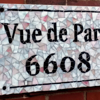 Mosaic sign on a brick wall reads "Vue de Parc 6608" in black letters and numbers.