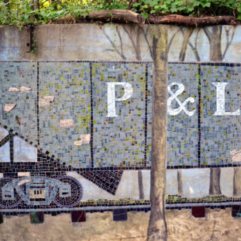 Mosaic mural depicts a train car with "P&LE" lettering, set against a backdrop of trees and a concrete wall.